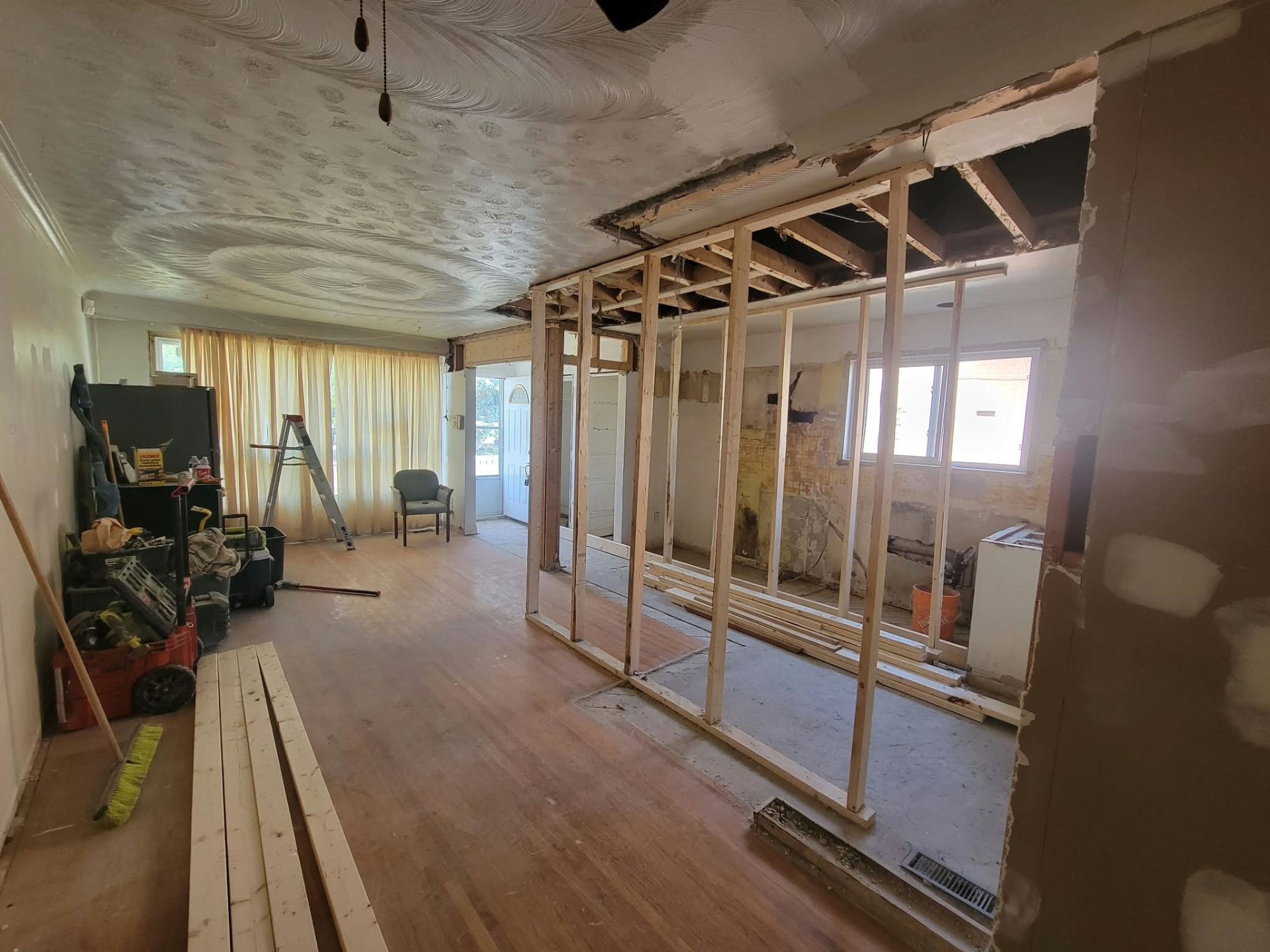 Renovation before: bare wood wall framing and exposed ceiling joists in a living room