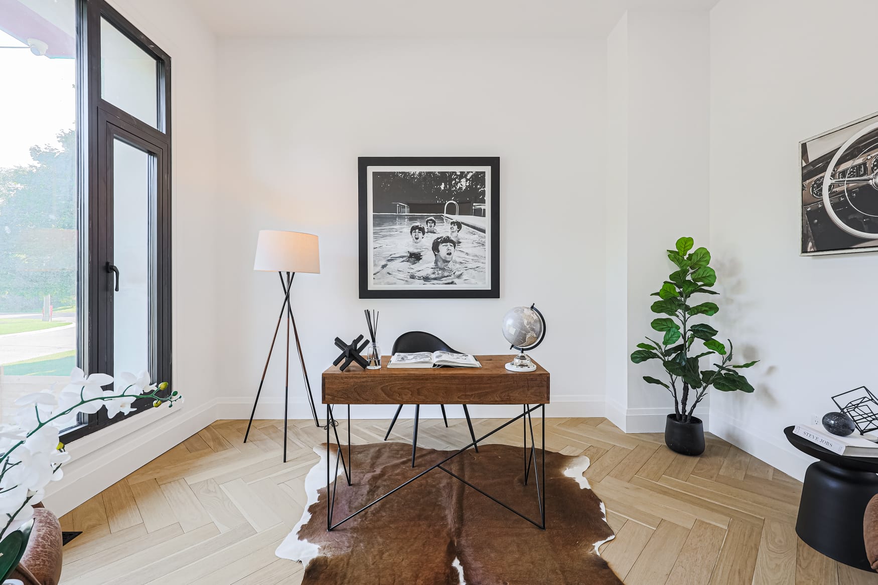 Styled study with walnut desk, tripod lamp and black and white photography