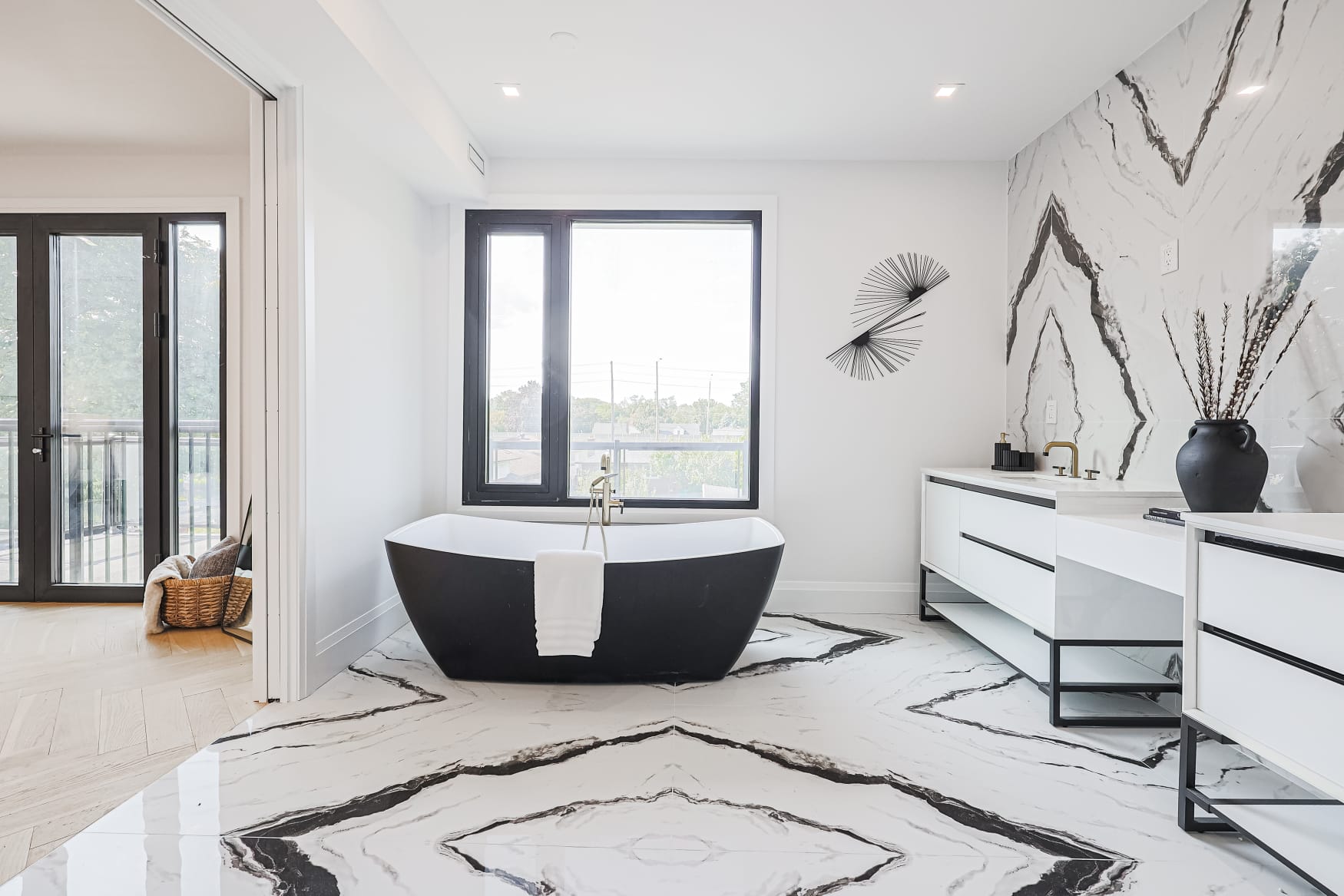 Ensuite bath with black freestanding tub and bookmatched marble