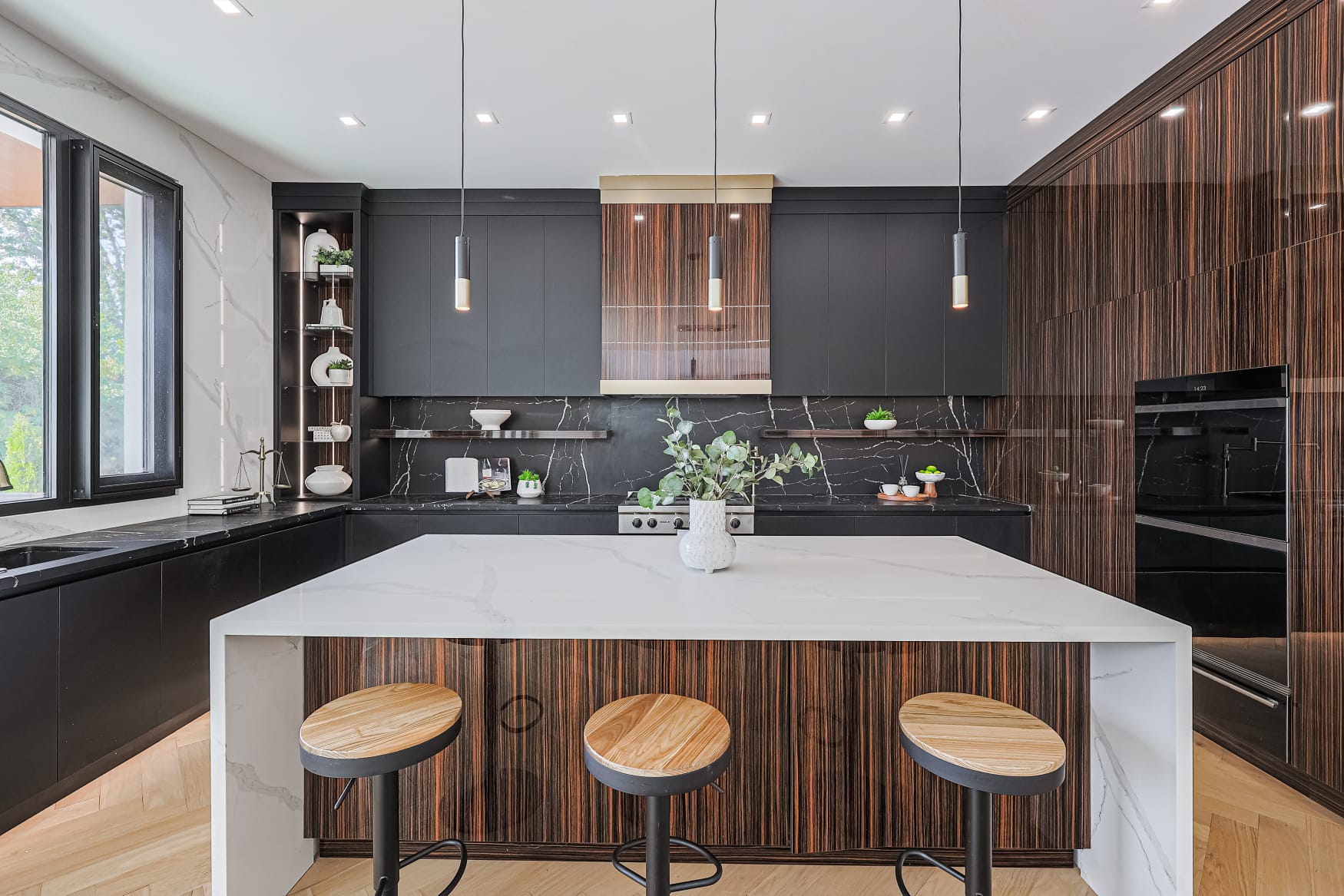 Modern kitchen with black cabinetry, ebony wood panels and a marble island