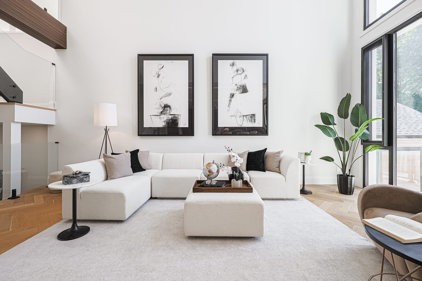 Bright living room with white sectional, framed charcoal artwork and herringbone oak floors