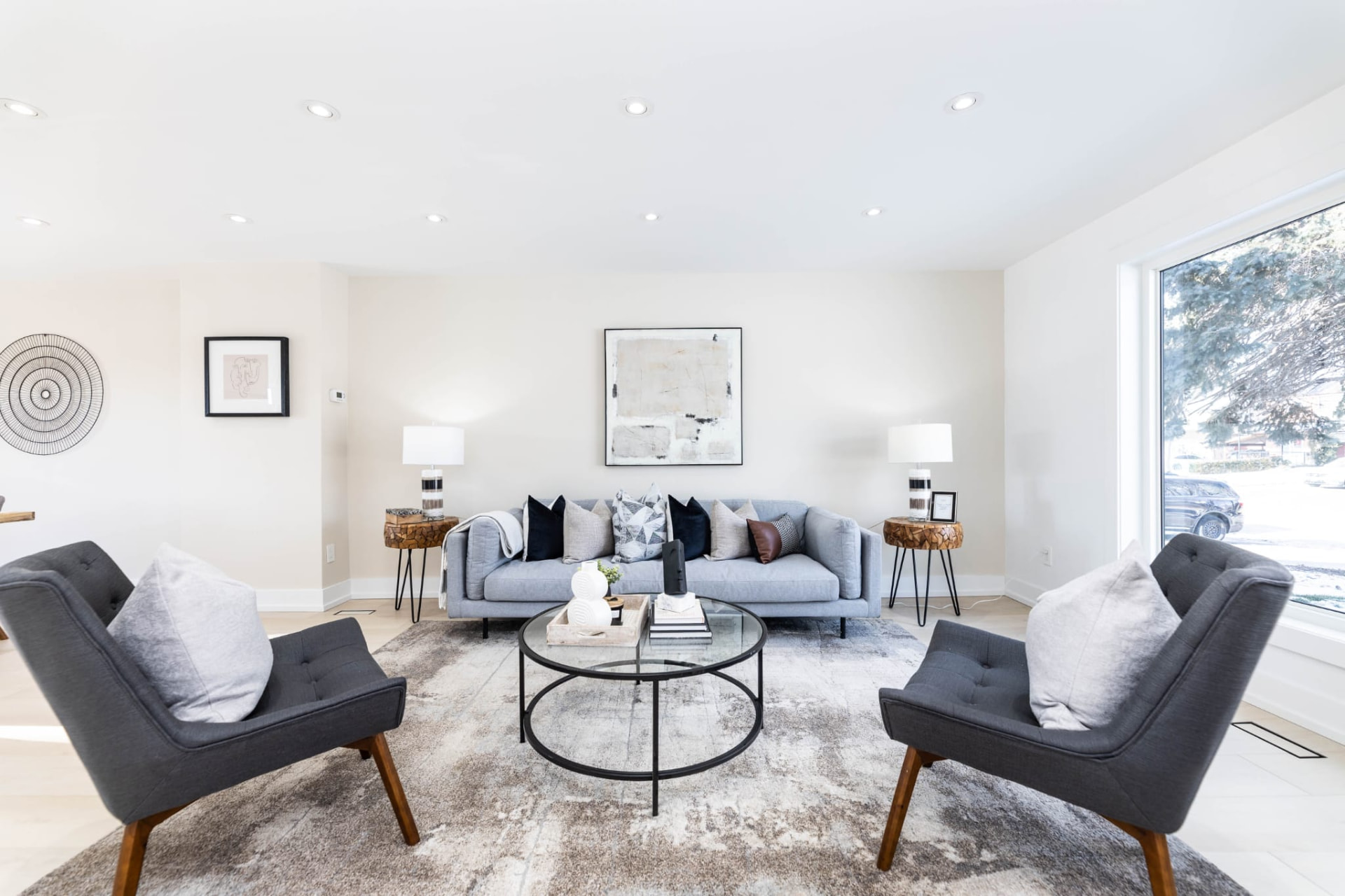 Staged living room with grey sofa, twin armchairs and abstract art