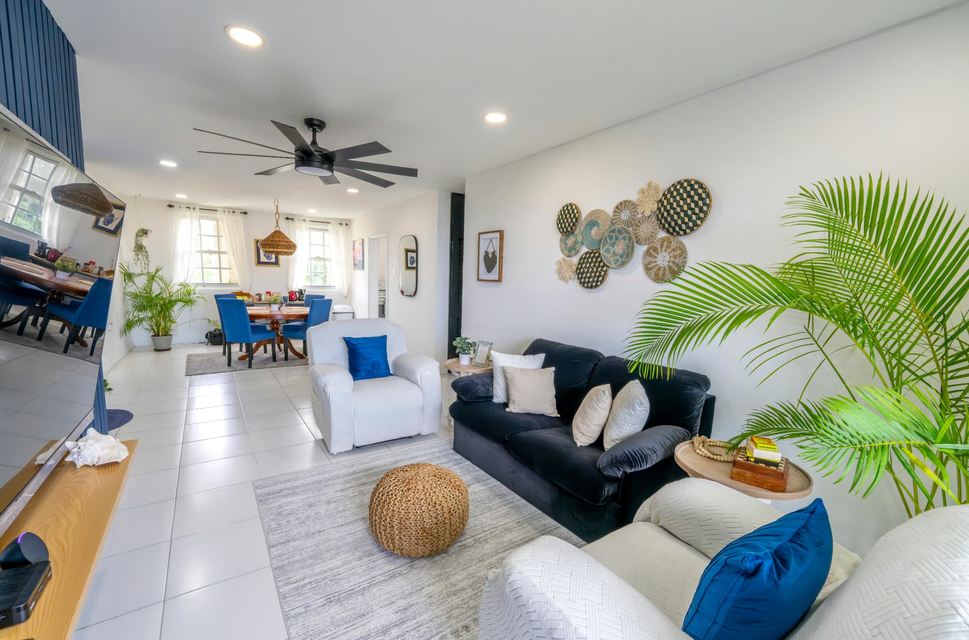 Bright internationally styled Airbnb living and dining space with blue accents and tropical greenery