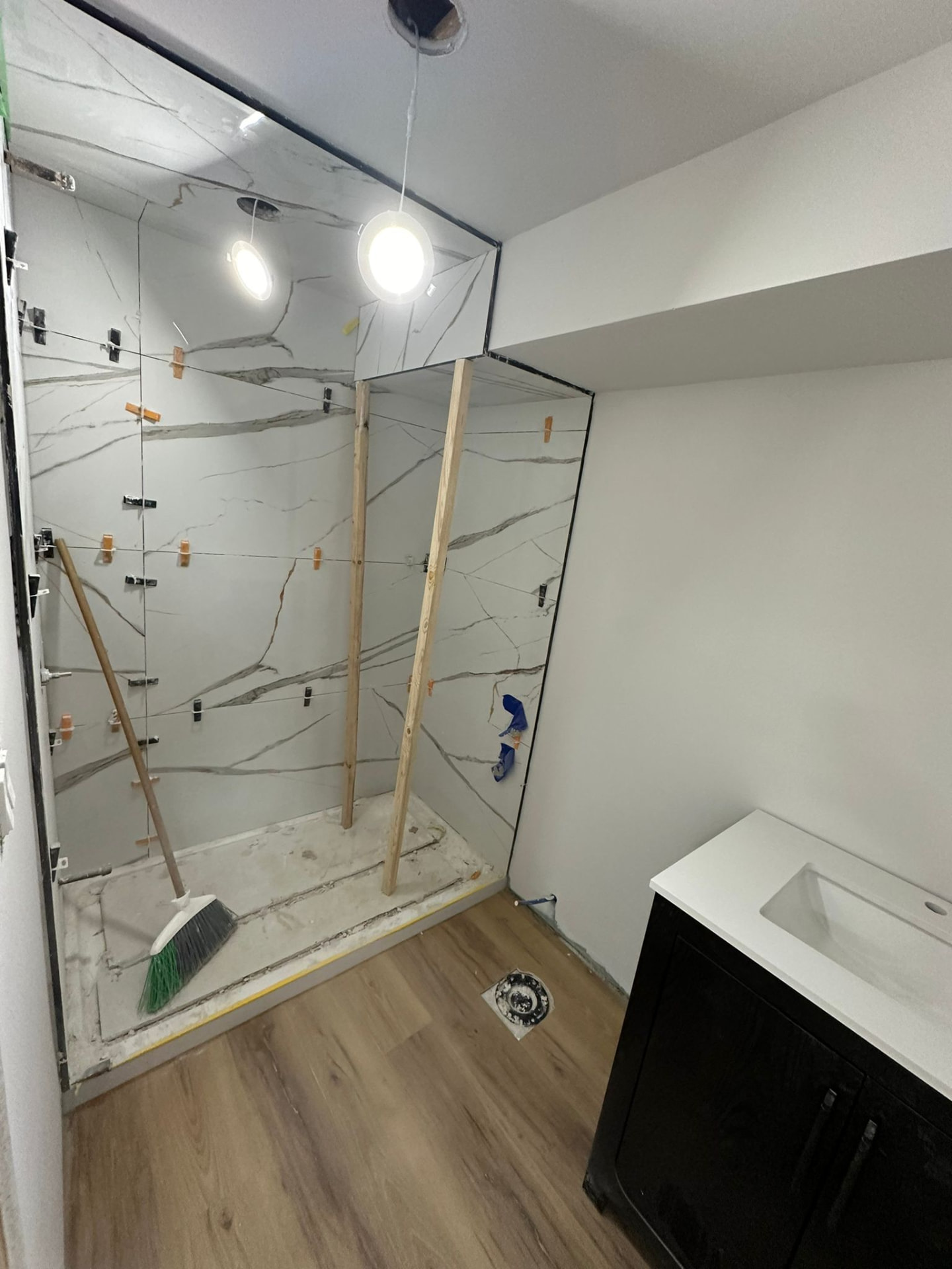 Bathroom renovation in progress — marble shower tiling underway with vanity in place
